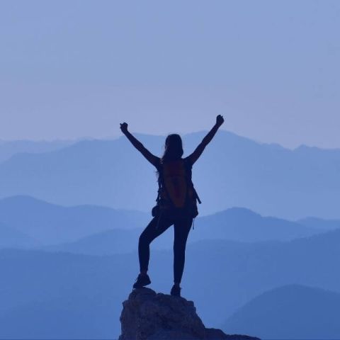 A silhouette of a hiker, surrounded by a serene blue mountain landscape.